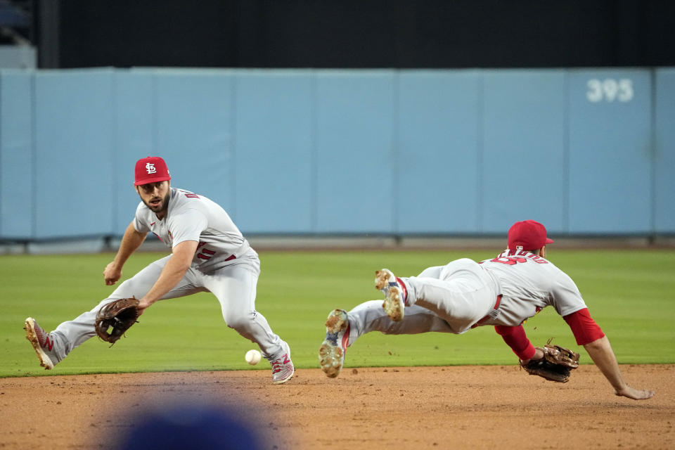 St. Louis Cardinals shortstop Paul DeJong, left, fields a ball hit by Will Smith as third baseman Nolan Arenado dives for it during the first inning of a baseball game Friday, April 28, 2023, in Los Angeles. Freddie Freeman was thrown out at second on the play. (AP Photo/Mark J. Terrill)