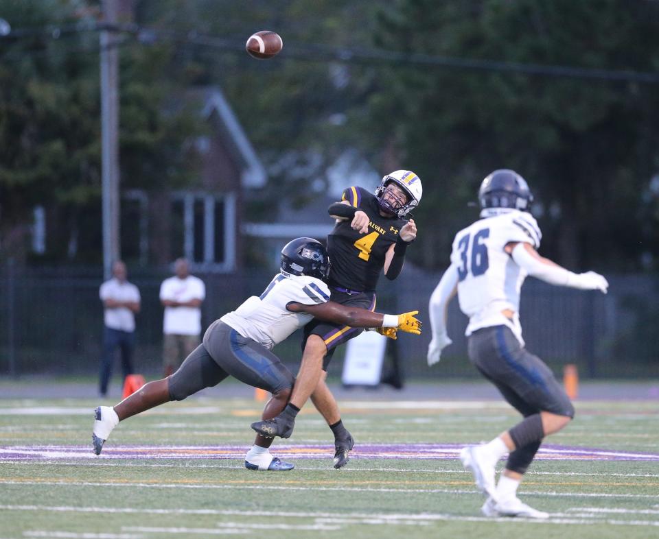 Calvary quarterback Jake Merklinger lets go of a pass as he is hit by Eagle's Landing's Trent Hood during Friday night's game at Calvary.