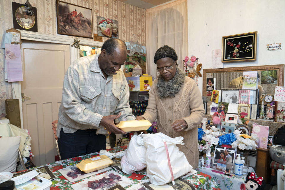 Sylius, left, and Bridgette Toussaint unpack their meals prepared by members of the Preston Windrush Covid Response team, in Preston, England, Friday Feb. 19, 2021. Once a week chief coordinator Glenda Andrew and her team distribute meals to people in Preston and surrounding communities in northwestern England that have recorded some of the U.K.’s highest coronavirus infection rates. The meal program grew out of Andrew’s work with Preston Windrush Generation & Descendants, a group organized to fight for the rights of early immigrants from the Caribbean and other former British colonies who found themselves threatened with deportation in recent years. (AP Photo/Jon Super)