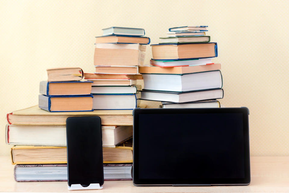 a stack of books with a phone and tablet leaning against it