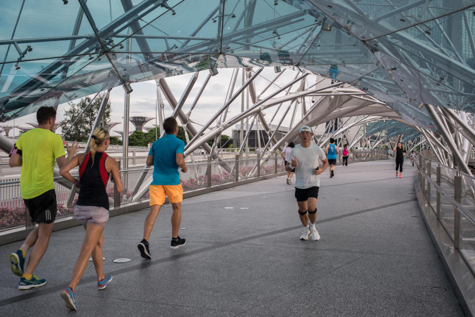 SINGAPORE - 2020/05/16: People jog along the helix bridge, a bridge that connects Marina Center to Marina South, during the Coronavirus (COVID-19) crisis. Singapore has so far confirmed 27,356 coronavirus cases, 22 deaths and 8,342 recovered, based on the latest update by the country's Ministry of Health. (Photo by Maverick Asio/SOPA Images/LightRocket via Getty Images)