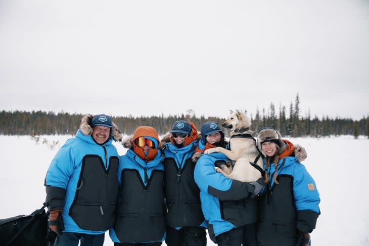 group of explorers and their dog smile in the arctic 