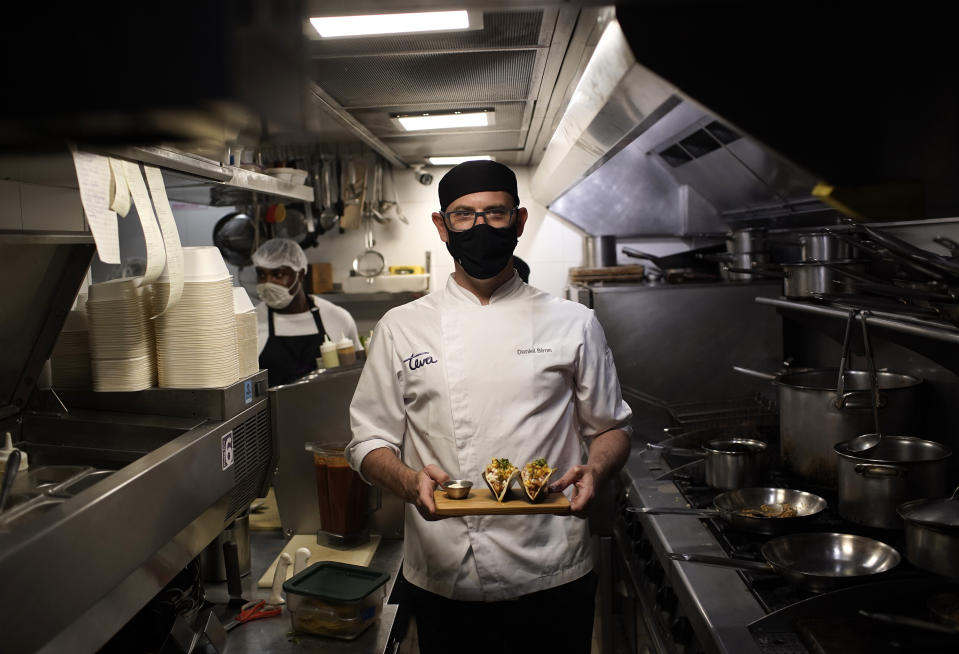 Head chef Daniel Biron poses for a photo holding a plate of his top-selling appetizer BBQ jackfruit tacos at the plant-based restaurant Teva, in the Ipanema neighborhood of Rio de Janeiro, Brazil, Thursday, Feb. 18, 2021. Historically, jackfruit has been consumed more by the poor or enslaved. (AP Photo/Silvia Izquierdo)