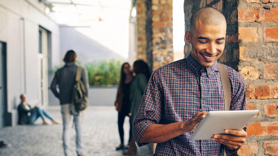 Shot of a young man using a digital tablet outdoors on campus.