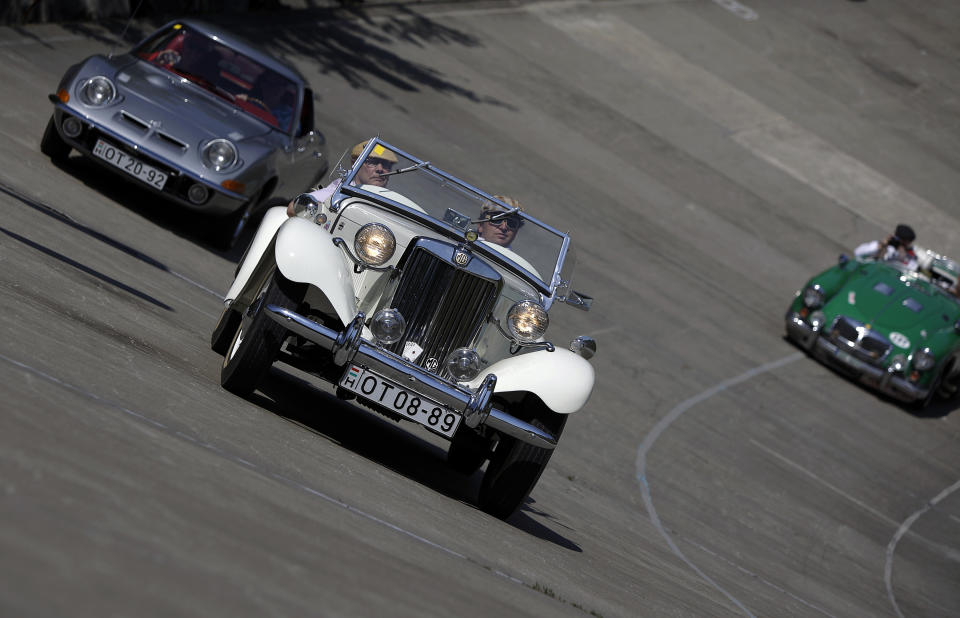 Drivers drive lead their vehicle on an oval track of a velodrome during an old timer car and motorcycle show in Budapest on May 1, 2012. The event brought life again into the 412 meter long Millennial Velodrome of Budapest, which was built in 1896 and is one of the oldest arenas for track cycling in Europe.  AFP PHOTO / PETER KOHALMIPETER KOHALMI/AFP/GettyImages