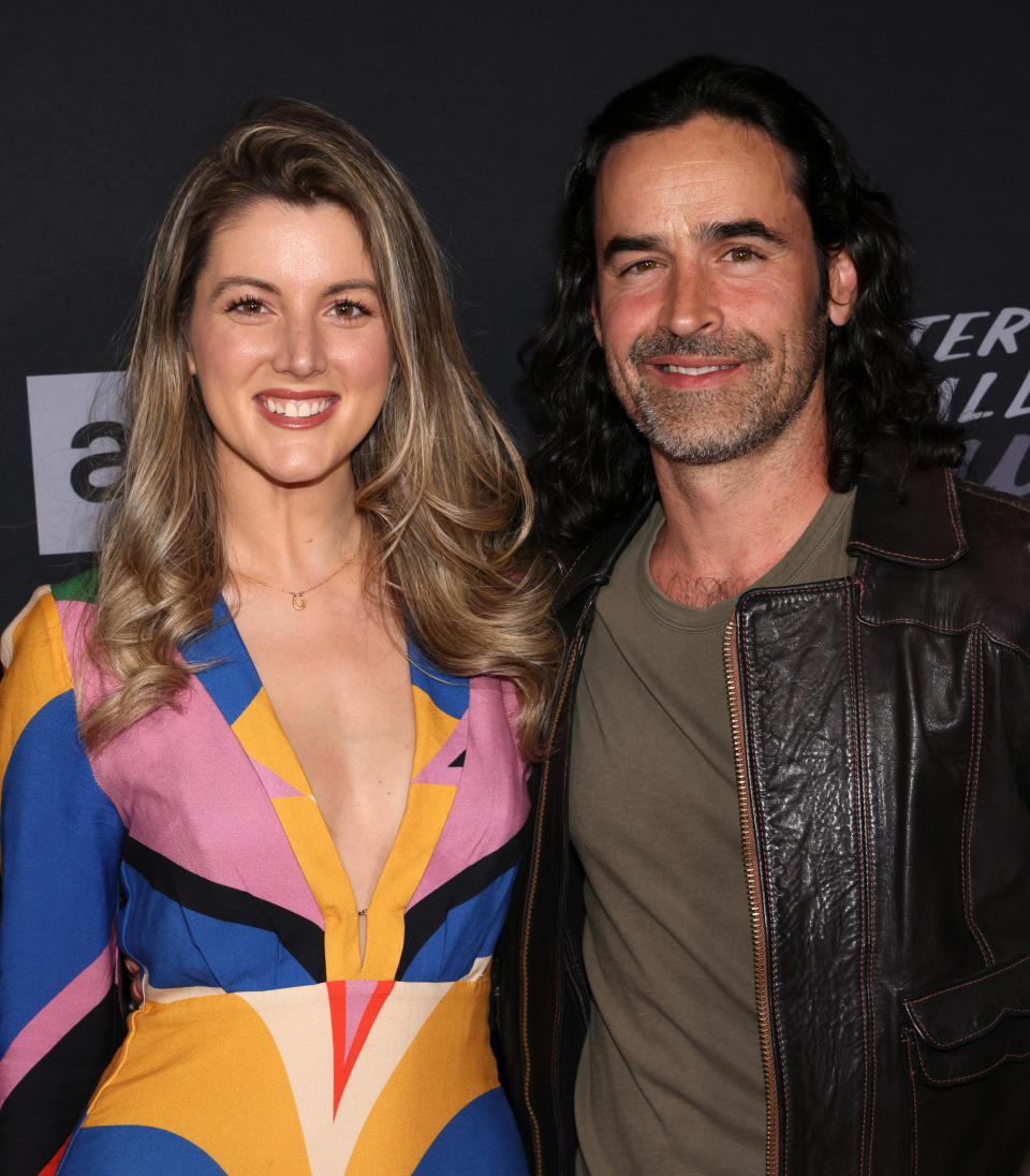 Smiling with a woman and wearing a leather jacket on the red carpet