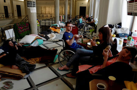 FILE PHOTO: Disabled Kuba Hartwich, 23, with other disabled people and their caretakers occupy a corridor during the eighth day of a protest against government proposals, demanding higher allowances at the Parliament building in Warsaw, Poland April 25, 2018. REUTERS/Kacper Pempel/File Photo