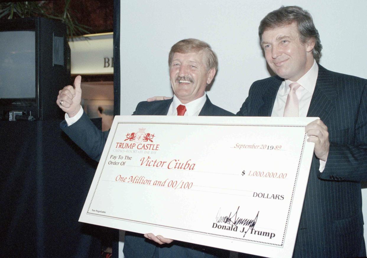 Victor Ciuba, left,  gives the thumb's up sign as he gets a $1 million check from Donald Trump in new York, on Sept. 20, 1990, after winning Trump Castle's See and Win A Million contest.