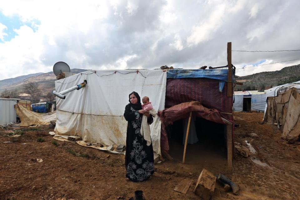 In this Tuesday, March 11, 2014 photo, Mervat, 31, stands outside of her tent as she holds her 9-month-old daughter Shurouk, at camp for Syrian refugees camp in Kab Elias, in Lebanon's Bekaa Valley. Trapped in her northern Syrian village by fighting, Mervat watched her newborn baby progressively shrink. Her daughter’s dark eyes seemed to grow bigger as her face grew more skeletal. Finally, Mervat escaped to neighboring Lebanon, and a nurse told her the girl was starving. Such stark malnutrition was rare in Syria in the past, but as the country’s conflict enters its fourth year, international aid workers fear malnutrition is rising among children in Syria and among refugees amid the collapse in the health care system.(AP Photo/Bilal Hussein)