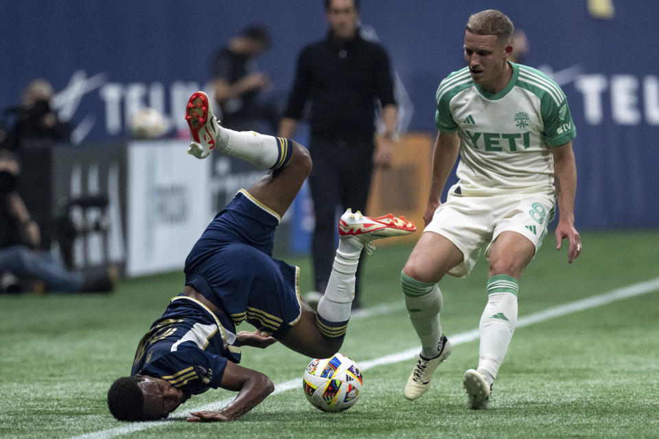 Vancouver Whitecaps' Ali Ahmed, left, falls in front of Austin FC's Alexander Ring (8) as they vie for the ball during the first half of an MLS soccer match in Vancouver, British Columbia, on Saturday, May 4, 2024. (Ethan Cairns/The Canadian Press via AP)