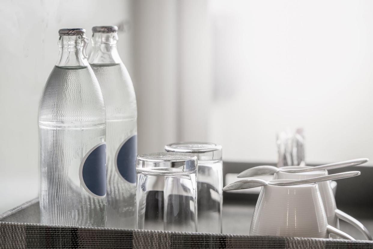 two bottles of mineral water in the hotel room, as well as clean glasses on a tray.