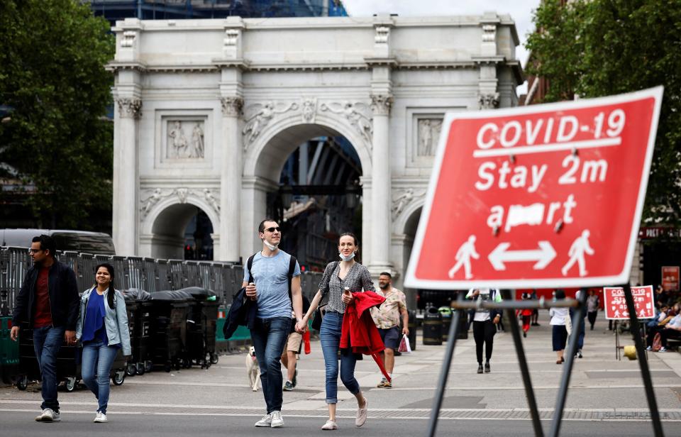 Pedestrians walk past a sign asking people to social distance, near Marble Arch in central London  (Photo: TOLGA AKMEN via Getty Images)