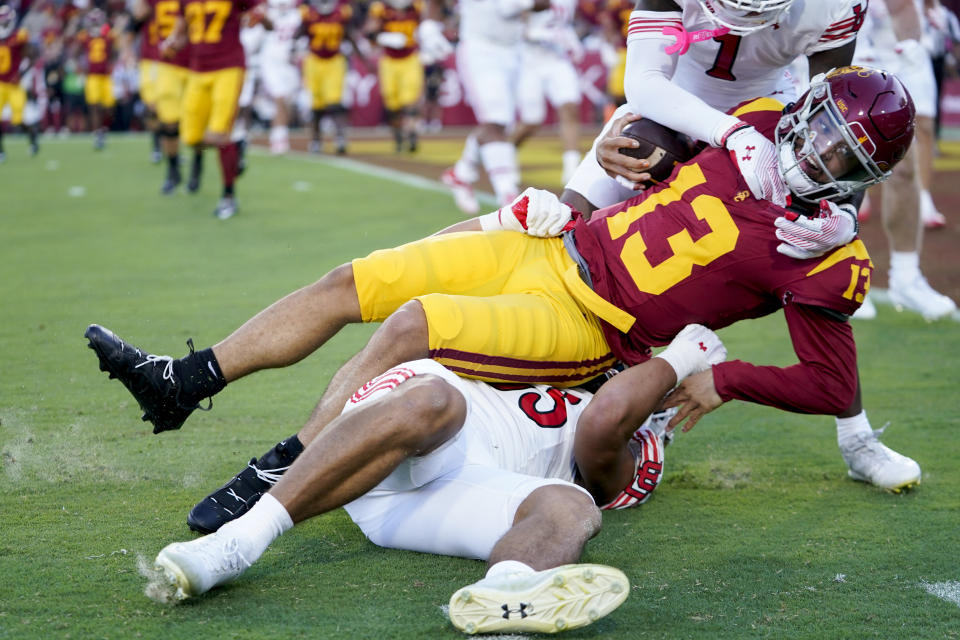 Southern California quarterback Caleb Williams (13) is tackled by Utah defensive end Jonah Elliss, bottom, and cornerback Miles Battle (1) during the first half of an NCAA college football game, Saturday, Oct. 21, 2023, in Los Angeles. (AP Photo/Ryan Sun)