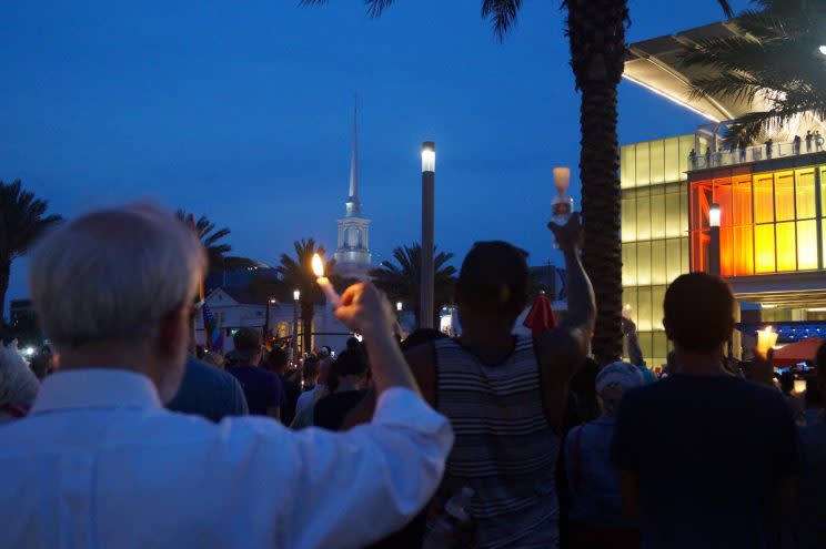 People hold up candles to honor the Pulse shooting victims with the First United Methodist Church in the background, in downtown Orlando on June 13, 2016. (Photo: Michael Walsh/Yahoo News)