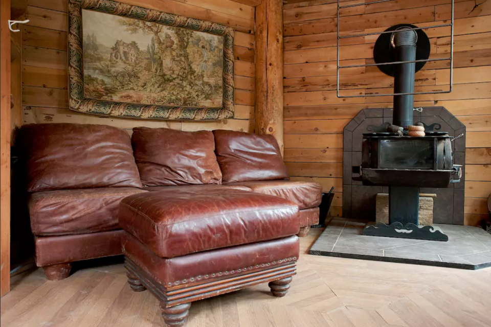 <p>The two-storey cabin has a beautiful wooded interior with leather couches, and a wood-burning fireplace. (Airbnb) </p>