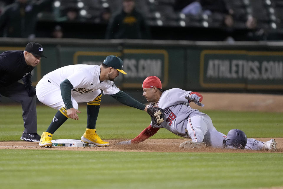 Oakland Athletics third baseman J.D. Davis, left, tags out Washington Nationals' Trey Lipscomb (38) during the 10th inning of a baseball game in Oakland, Calif., Friday, April 12, 2024. (AP Photo/Tony Avelar)