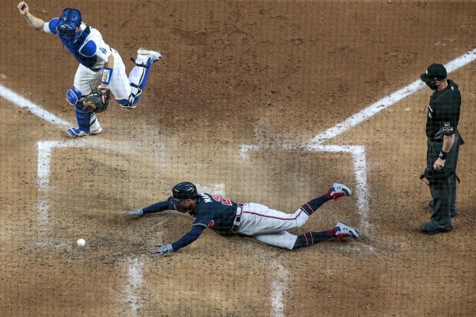 The Braves' Nick Markakis slides past Dodgers catcher Will Smith to score in Game 2 of the 2020 NLCS