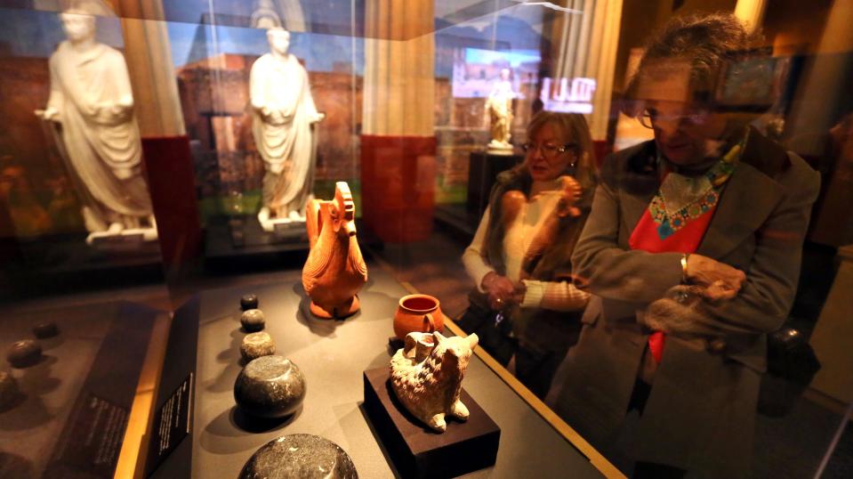 Exhibit visitors examine everyday items excavated from Pompeii.
