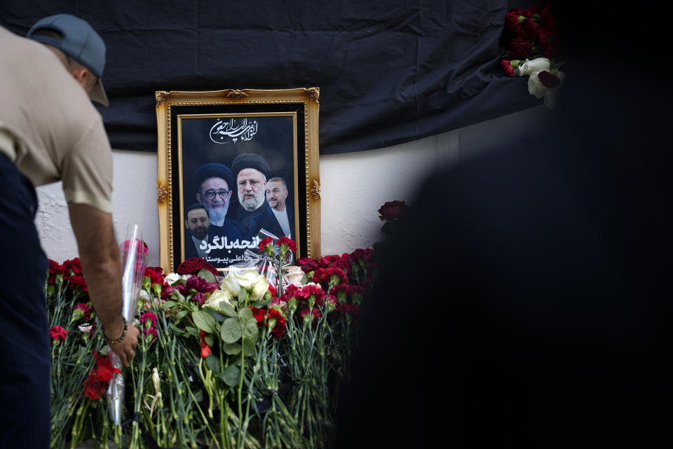 Un hombre coloca flores cerca de una fotografía del presidente iraní Ebrahim Raisi y sus colegas en un sitio de homenaje improvisado en la embajada de Irán en Moscú, Rusia, el 20 de mayo de 2024. (AP Foto/Alexander Zemlianichenko)