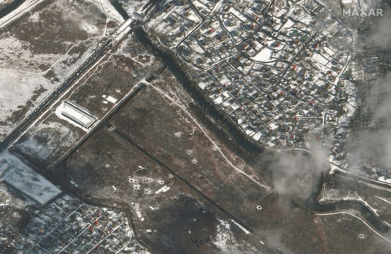 A satellite image shows a damaged bridge and craters in a field in Irpin.