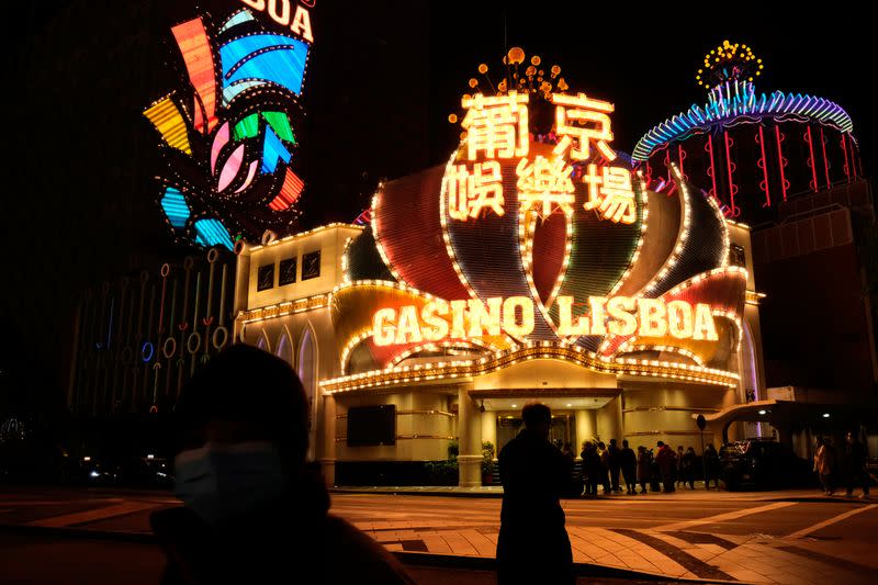 People wearing masks walk in front of Casino Lisboa, before its temporary closing, following the coronavirus outbreak in Macau