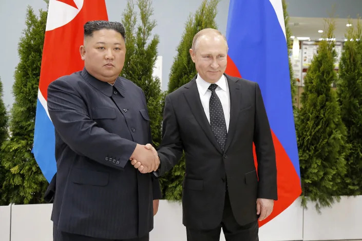 Russian President Vladimir Putin, right, and North Korean leader Kim Jong Un shake hands.