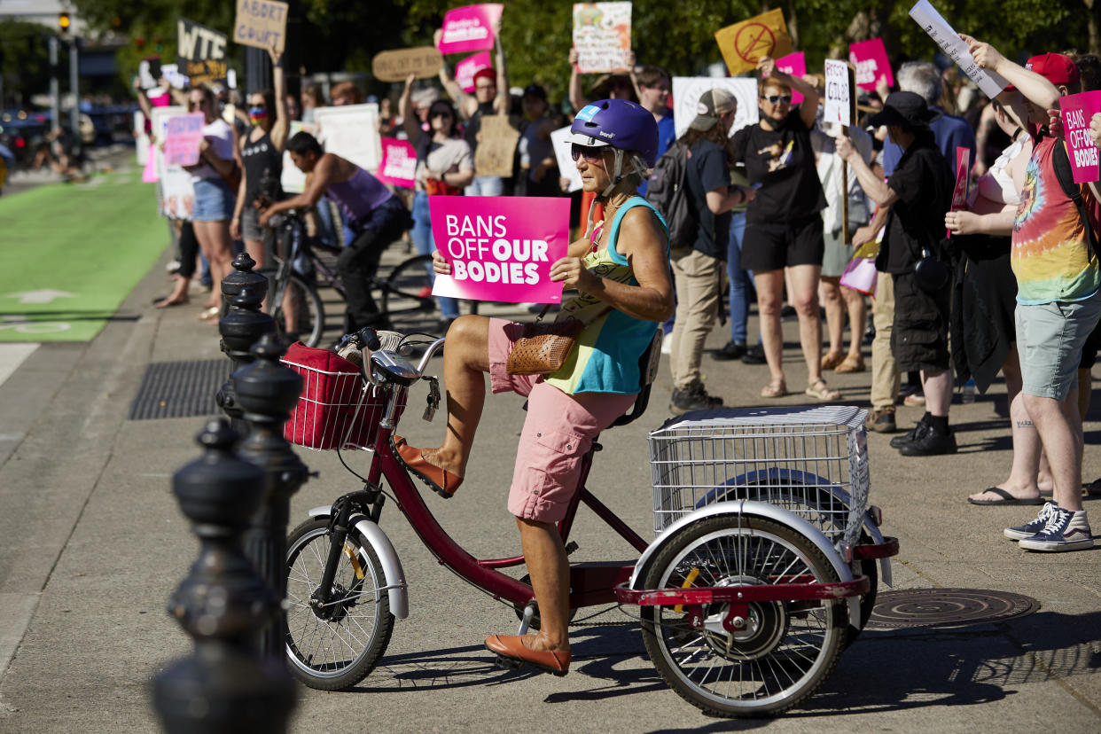 FILE - Protesters hold signs against the Supreme Court's decision to overturn Roe v. Wade in Portland, Ore., Friday, June 24, 2022. Oregon's Department of Justice has launched a new abortion hotline offering free legal advice to callers. People who call the hotline will receive a call back within 48 hours from a lawyer offering free legal advice on the status of abortion rights in Oregon. (AP Photo/Craig Mitchelldyer, File)