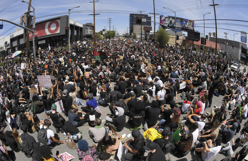 In this photo taken with a wide angle lens, demonstrators sit in an intersection during a protest over the death of George Floyd, Saturday, May 30, 2020, in Los Angeles. Protests were held in U.S. cities over the death of Floyd, a black man who died after being restrained by Minneapolis police officers on May 25. (AP Photo/Mark J. Terrill)