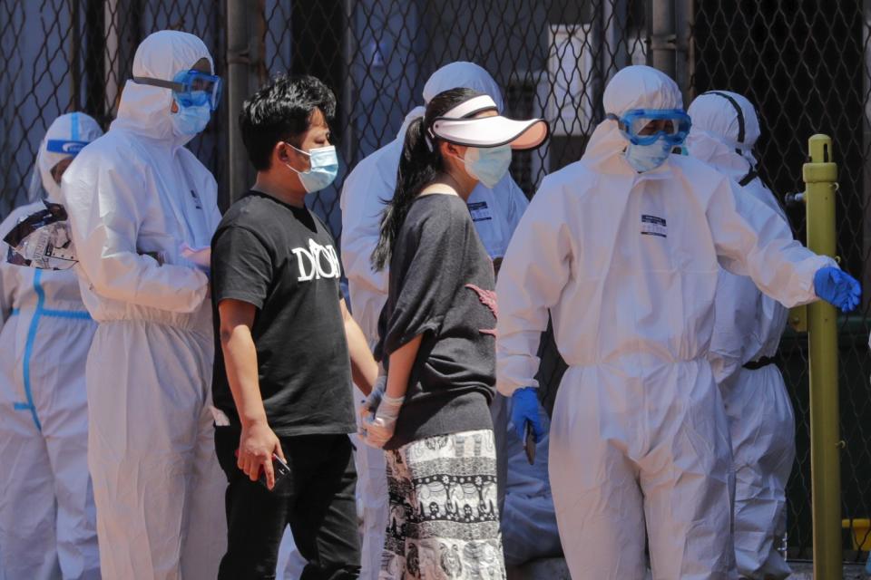 Workers in protective suits direct people being tested for COVID-19 at a Beijing stadium.