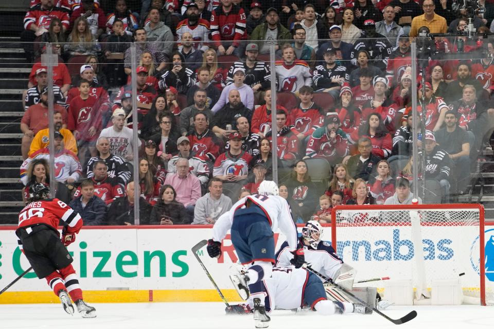 New Jersey Devils center Jack Hughes, left, scores a goal past Columbus Blue Jackets goaltender Michael Hutchinson during the first period of an NHL hockey game Thursday, April 6, 2023, in Newark, N.J. (AP Photo/Mary Altaffer)