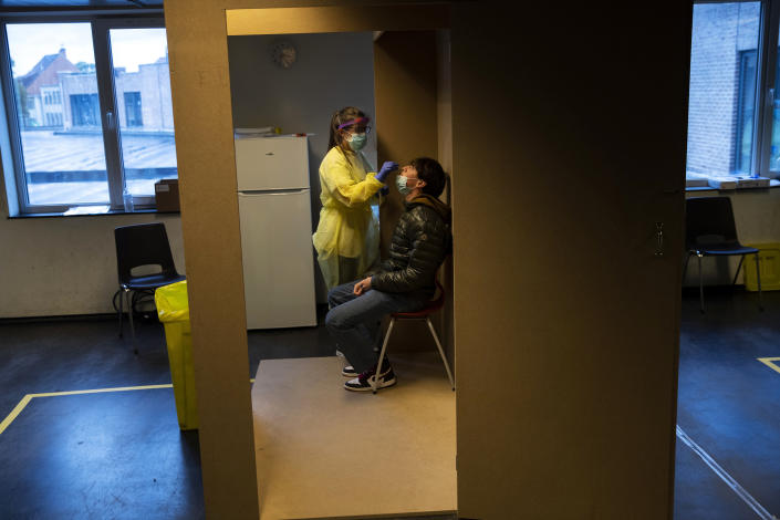 A medical worker, wearing full protective gear, takes a nose swab from a patient to be tested for COVID-19 in a Red Cross test centre in Brussels, Tuesday, Oct. 13, 2020. Authorities in Belgium, one of the European countries hit hardest by the coronavirus, are warning that the number of cases is rising at a "quite alarming" rate and that 10.000 people could be catching the virus each day by the end of the week. (AP Photo/Francisco Seco)