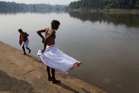 Men get dressed after bathing in Periyar river at Okkal village in Ernakulam, Kerala, India, September 25, 2018. REUTERS/Sivaram V