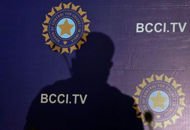 FILE PHOTO: The shadow of a man falls on a backdrop with the logo of the India's cricket board BCCI before the start of a news conference to announce its cricket team's coach, in Mumbai,