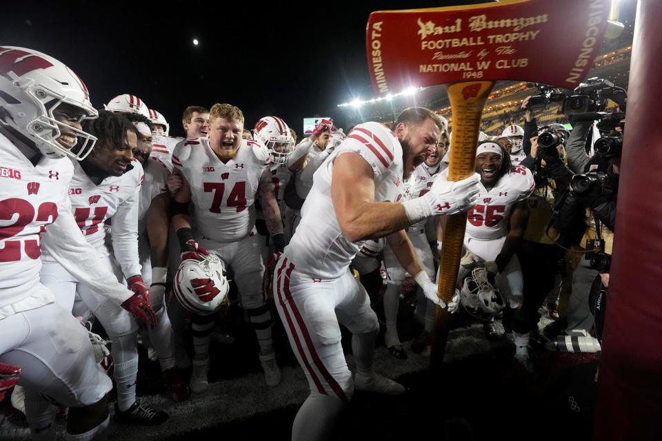 Wisconsin tight end Hayden Rucci (87) and team celebrate with the Paul Bunyan Axe after their game on November 25, 2023, at Huntington Bank Stadium in Minneapolis, Minnesota. Wisconsin beat Minnesota 28-14. The team uses the ceremonial axe to act out cutting down the goalposts.