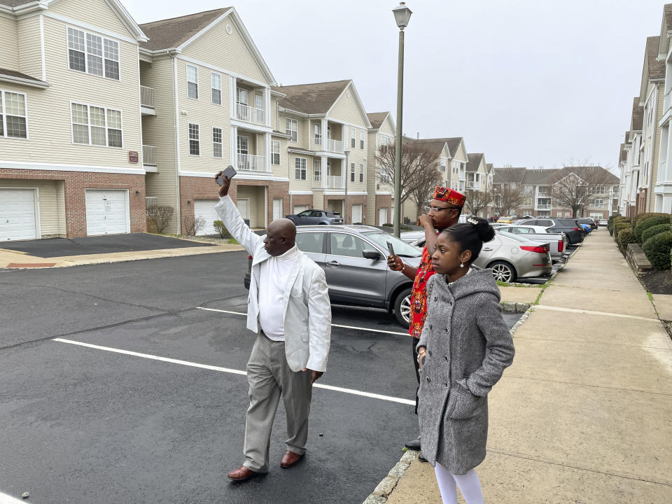 From left, Prince Dwumfour, Peter Ezechukwu and Nicole Teliano visit the scene of the fatal shooting of their family member, Eunice Dwumfour, in Sayreville, N.J., April 5, 2023. Eunice Dwumfour, a Sayreville council member, was gunned down Feb. 1 as she arrived home in Sayreville. (AP Photo/Maryclaire Dale)