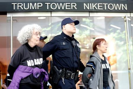 A New York City Police officer (NYPD) escorts protestors after making arrests for demonstrating in Trump Tower in New York, U.S., April 13, 2017. REUTERS/Brendan McDermid