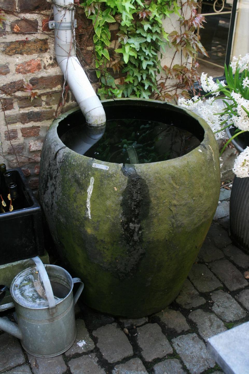 In this April 19, 2009 photo, rainscaping features can be expensive and complicated or simple and cheap, like this rain barrel capturing water from a downspout on a rural home in northern Belgium. The gardener simply dips a spray can into the surplus when she wants to water her plants. (AP Photo/Dean Fosdick)