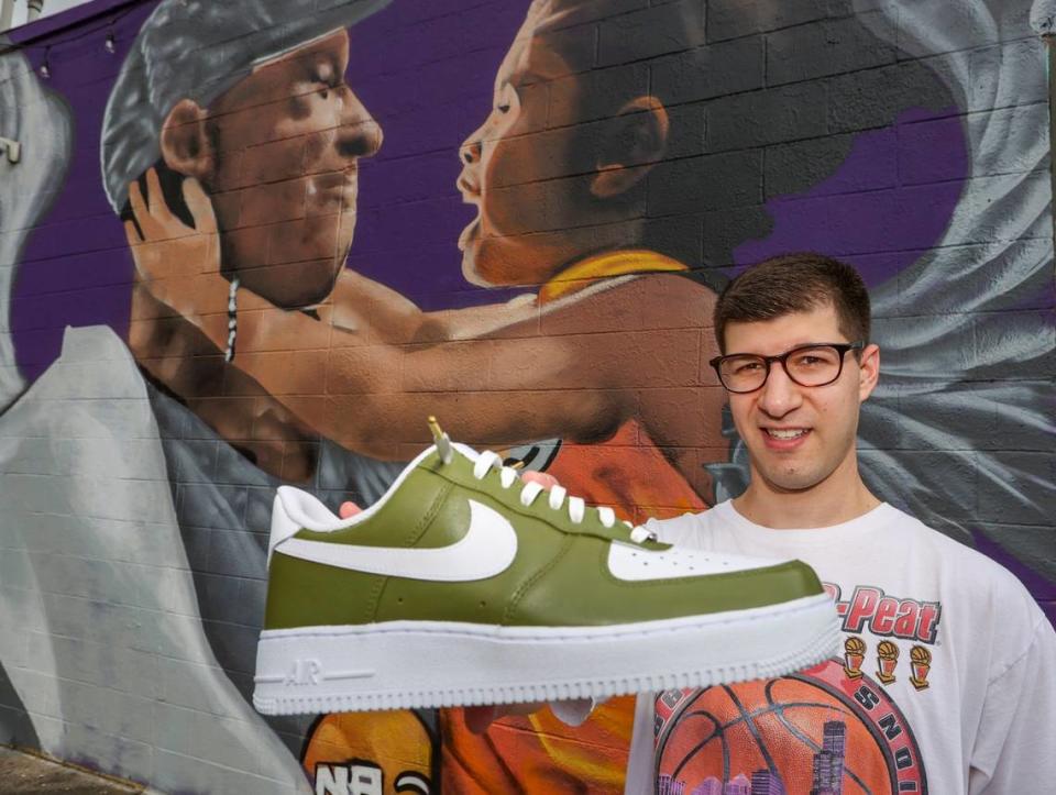 Jeremy Recoon, who creates custom Nikes for athletes and celebrities, shows examples of his work by the Kobe Bryant mural in Charlotte.