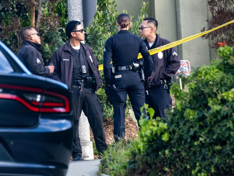 Officers stand near police tape at a home in Benedict Canyon.