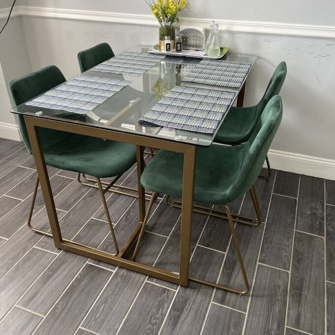 A set of four green chairs at a clear dining room table.