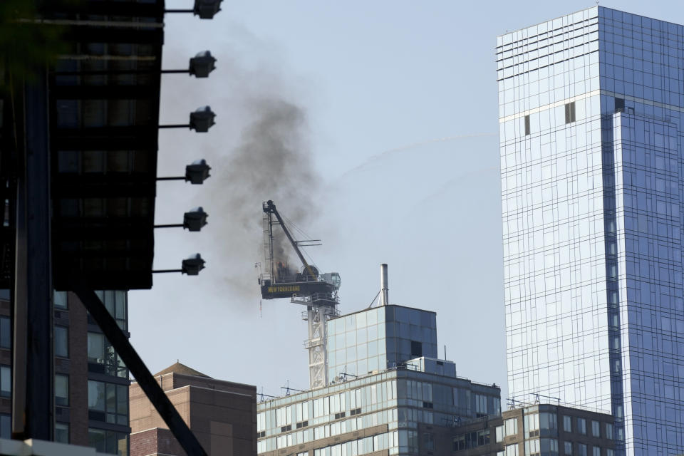 Smoke rises from a construction crane that caught fire in Manhattan, Wednesday, July 26, 2023, in New York. The crane lost its long arm, which smashed against a nearby building, dangled and then plummeted to the street as people ran for their lives on the sidewalk below. Some people suffered minor injuries, but no one died, according to Mayor Eric Adams .(AP Photo/Seth Wenig)