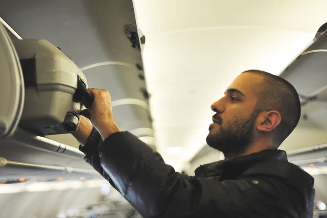 <p>Getty</p> Stock image of a passenger getting their bag out of the overhead bin.