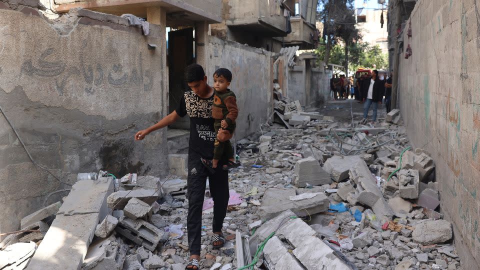 A Palestinian youth carries a child as he walks through rubble in Rafah's Tal al-Sultan district on Tuesday. - AFP/Getty Images