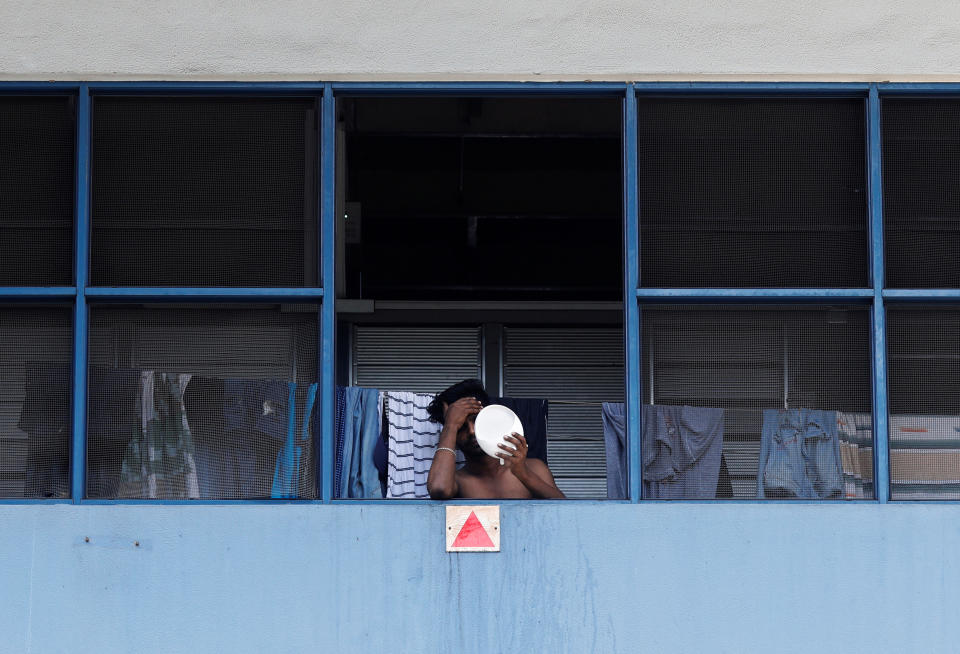 A migrant worker living in a factory-converted dormitory looks into a mirror as he serves his stay-home notice during the coronavirus outbreak here on 22 April, 2020. (PHOTO: Reuters)