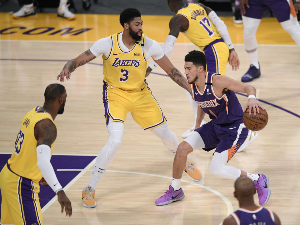 LOS ANGELES, CALIFORNIA - JUNE 03: Devin Booker #1 of the Phoenix Suns dribbles in front of Anthony Davis #3 and LeBron James #23 of the Los Angeles Lakers in the first quarter during game six of the Western Conference first round series at Staples Center on June 03, 2021 in Los Angeles, California. (Photo by Harry How/Getty Images) NOTE TO USER: User expressly acknowledges and agrees that, by downloading and or using this photograph, User is consenting to the terms and conditions of the Getty Images License Agreement.