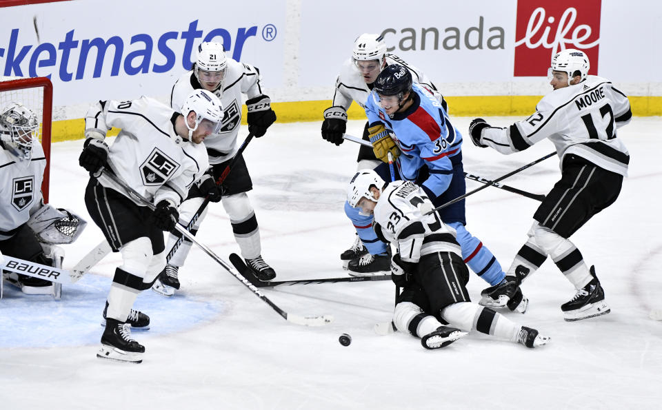 Los Angeles Kings' Viktor Arvidsson (33) holds the stick of Winnipeg Jets' Morgan Barron (36) as Pierre-Luc Dubois (80) clears the puck during the third period of an NHL hockey game in Winnipeg, Manitoba, on Monday, April 1, 2024. (Fred Greenslade/The Canadian Press via AP)