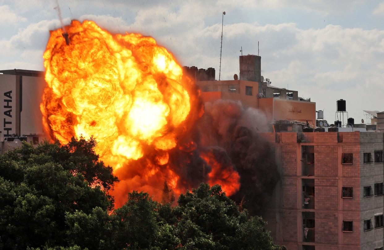 <p>A ball of fire engulfs the Al-Walid building which was destroyed in an Israeli airstrike on Gaza city on Thursday</p> (AFP via Getty Images)