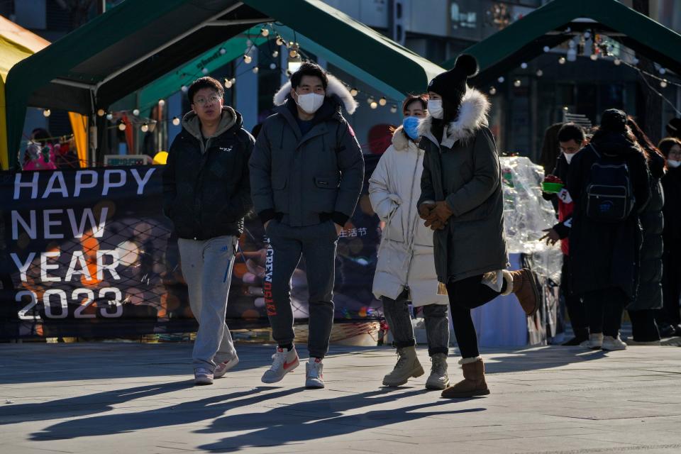 People wearing face masks walk through a bazaar outside a commercial office building in Beijing (Copyright 2022 The Associated Press. All rights reserved)