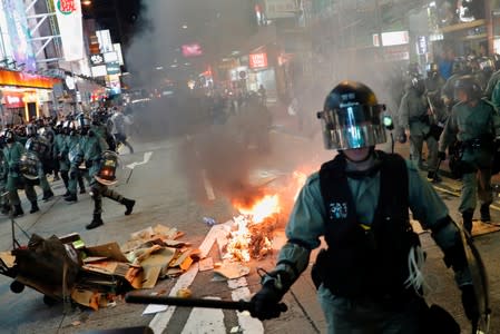 Riot police walk near a fire set by anti-extradition bill protesters during a protest at Prince Edward in Hong Kong