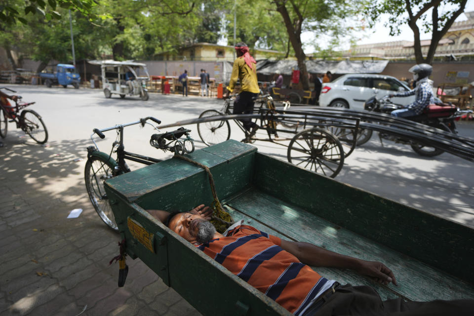 An Indian laborer sleeps on a push cart in the shade of a tree on a hot day in Prayagraj, northern Uttar Pradesh state India, Monday, May 22, 2023. The heat wave in the state is likely to continue for another two days, an Indian Meteorological Department official said. (AP Photo/Rajesh Kumar Singh)